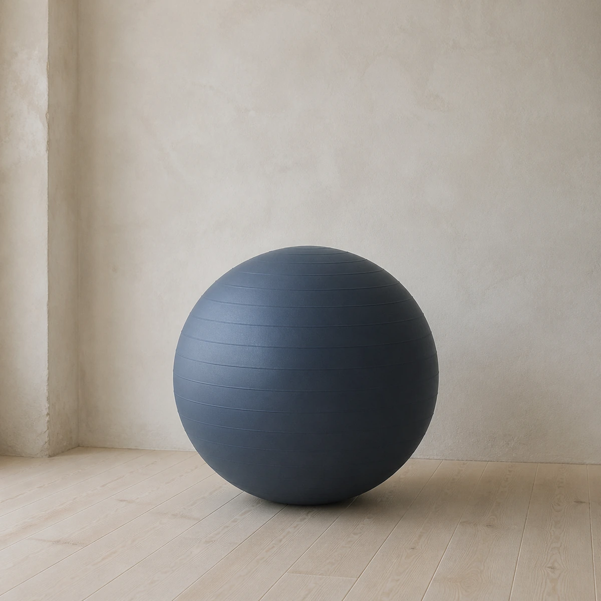 Still Water Balance Ball in deep slate against a plaster wall
